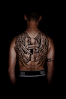 person with kneeling angel back tattoo