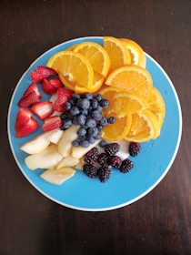 A small plate with sliced apple, papaya, banana, and berries for birds.