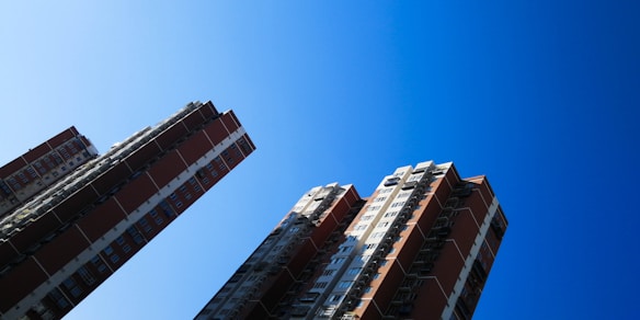 Tall residential buildings with a deep blue sky in the background, showcasing a modern architectural design with numerous windows.