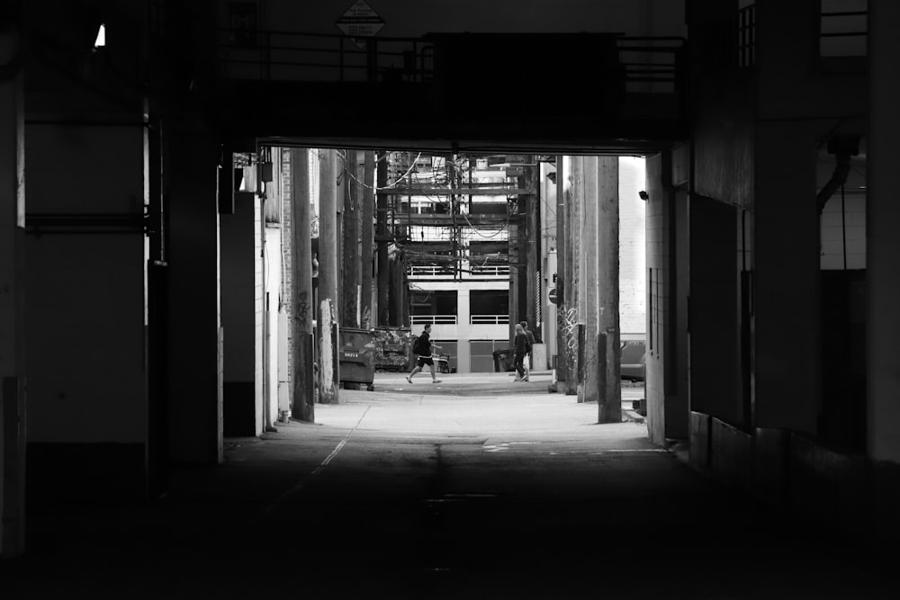 grayscale photo of man walking through tunnel