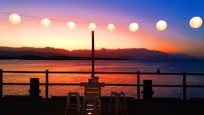 Sunset view over the wooden porch overlooking Lake Travis with warm string lights glowing