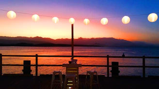 Sunset view from the 1,500 sq. ft. rooftop deck overlooking Lake Travis with soft string lights glowing.