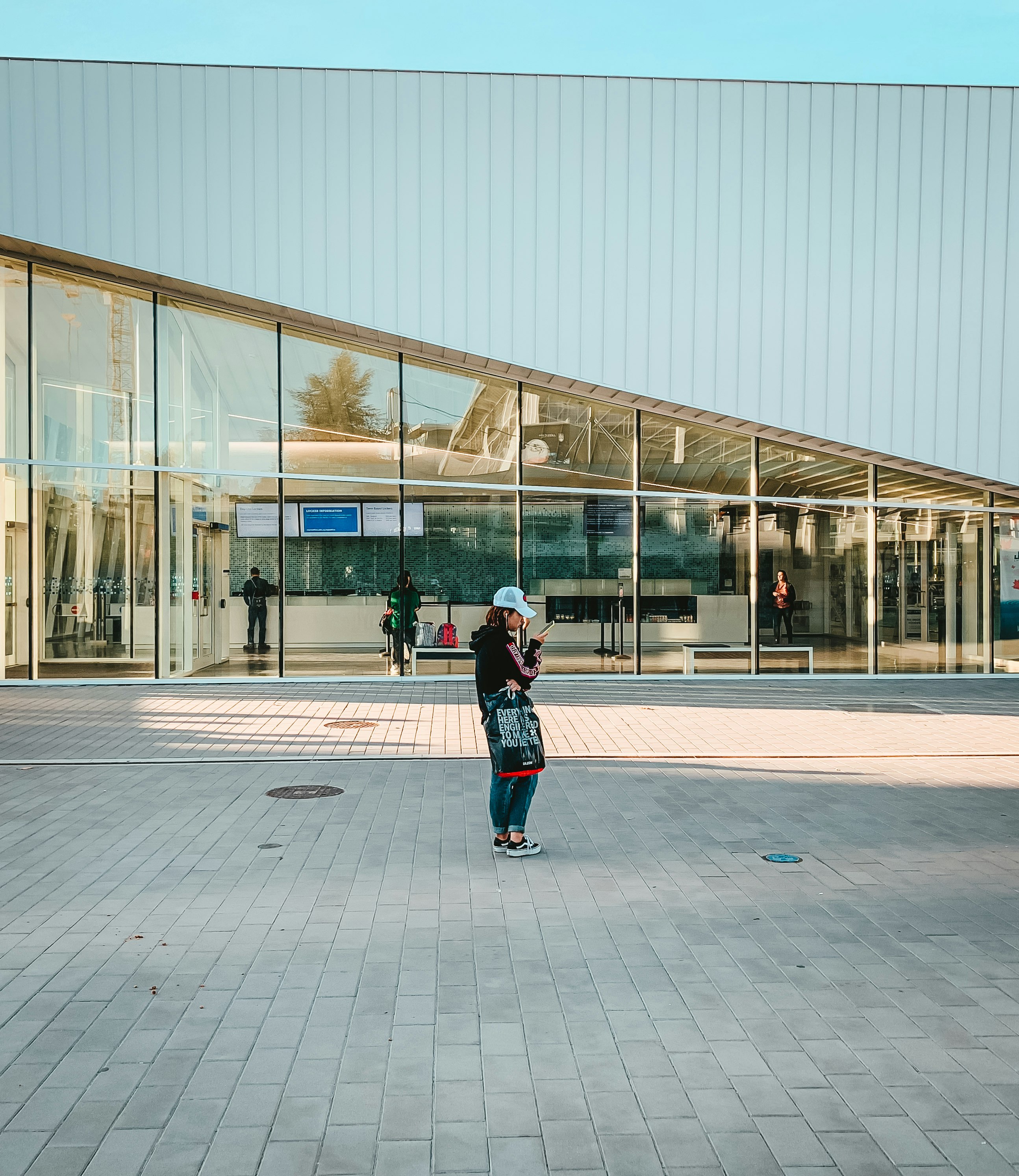 A shot of a girl looking at her phone, standing by UBC’s Aquatic Center building