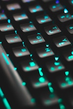 Close-up of hands typing on a modern keyboard with colorful backlighting in a tech store setting.
