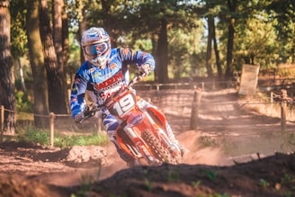 Dramatic shot of a motocross rider kicking up dust racing through a dense forest trail at sunset.