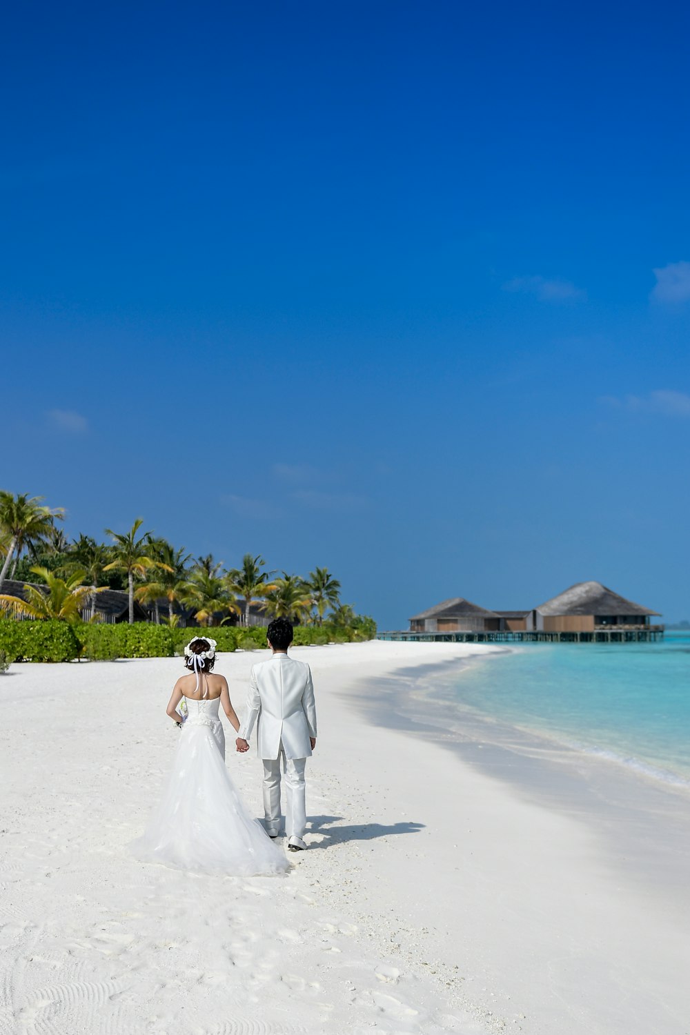 A newly married couple walks along a pristine beach in the Maldives