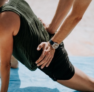 person pressing man back kneeling on blue towel