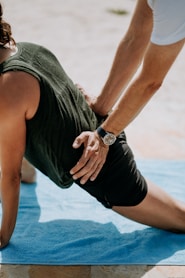 person pressing man back kneeling on blue towel