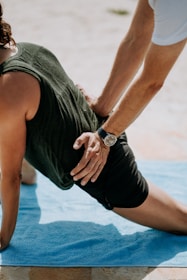 person pressing man back kneeling on blue towel