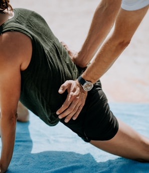 person pressing man back kneeling on blue towel