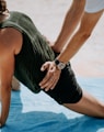 person pressing man back kneeling on blue towel