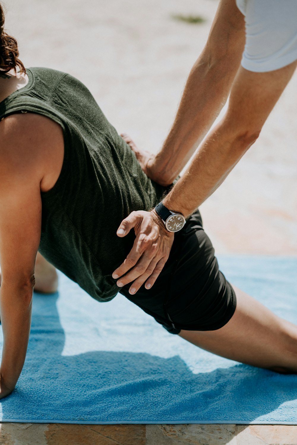 person pressing man back kneeling on blue towel