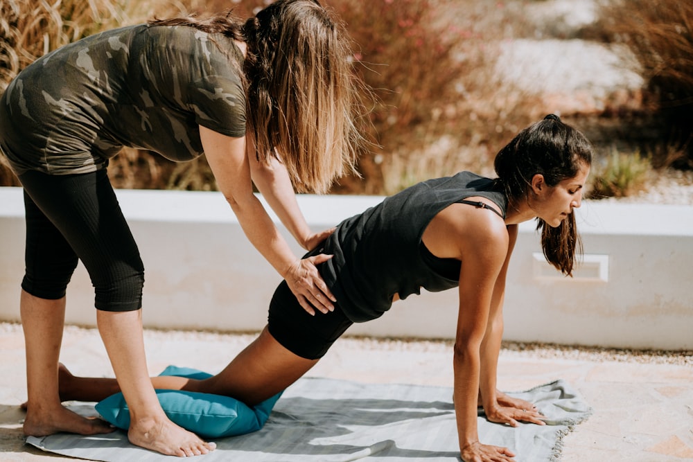 femme en débardeur noir et short noir agenouillée sur tapis