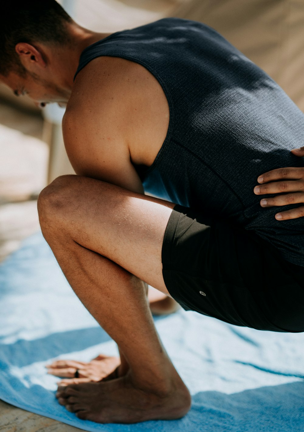 man in black shirt squatting on blue mat