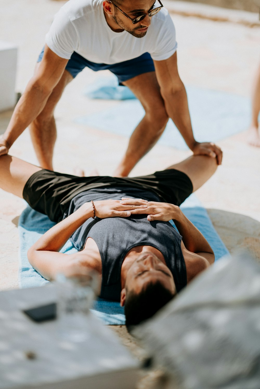 man pressing man's legs during daytime