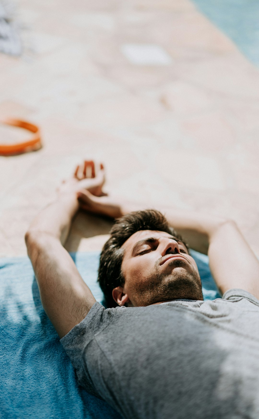 selective focus photography of man lying on blue cushion during daytime