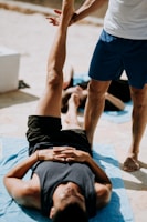 man lying on floor near man standing holding his leg