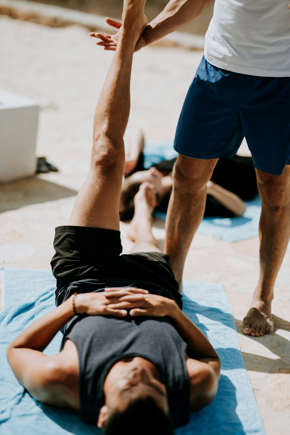 man lying on floor near man standing holding his leg