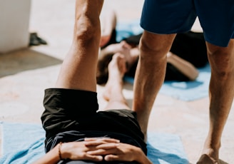man lying on floor near man standing holding his leg