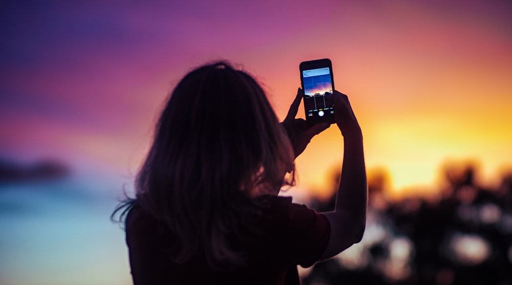 woman taking photo of sunset