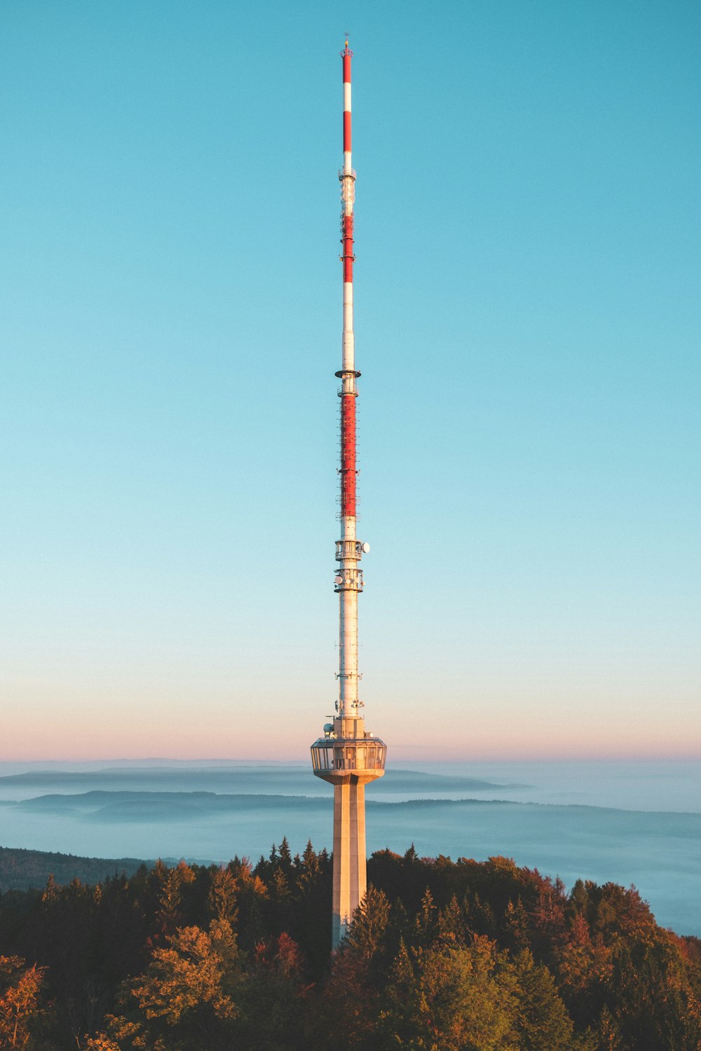 Torre vermelha e branca cercada por árvores