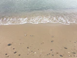 Gentle waves lapping against a quiet sandy shore at dawn.