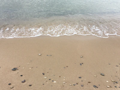 Gentle waves lapping against a quiet sandy shore at dawn.