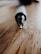 A close-up view of a pen resting on a wooden surface, focused on the pen tip. The background is softly blurred, giving prominence to the pen's metallic tip and sleek design.