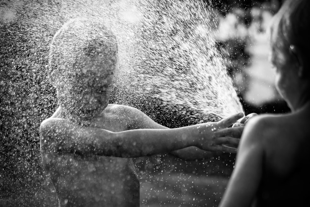 grayscale photo of boy playing water