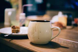 A plain white mug sitting on a wooden table.