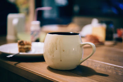 A plain white mug sitting on a wooden table.