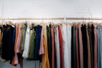 A pair of stylish pants displayed on a wooden hanger against a white wall