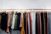 A row of Maison Galonné pants in five different colors hanging neatly in a boutique.