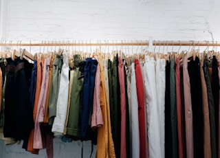 assorted-color clothes lot hanging on wooden wall rack