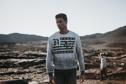 Close-up of a person wearing a bold graphic tee from North Stitch, standing against a rugged northern landscape.