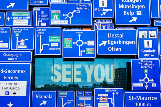 See You displayed on glass window with blue road signage hanging outside the window
