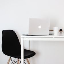 Minimalistic workspace with a sleek laptop and a white coffee cup on a clean desk.