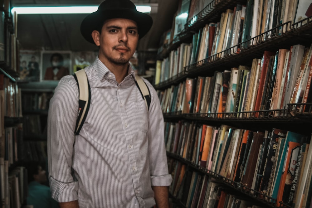 man standing beside bookcase