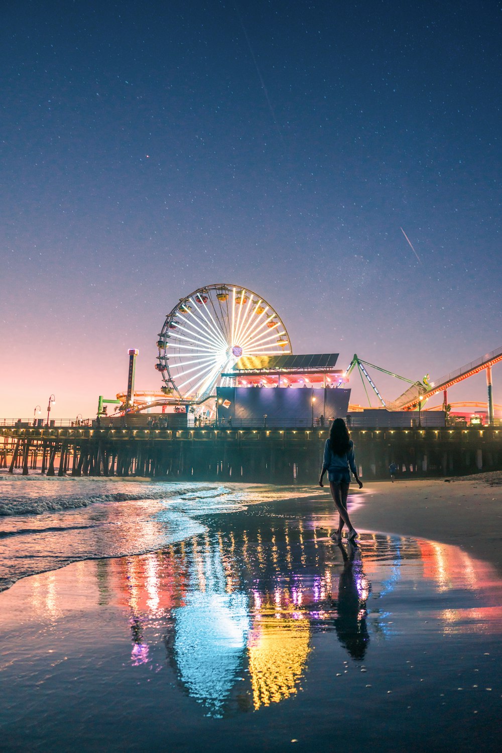 woman standing on shore front of lighted Ferries wheel at night