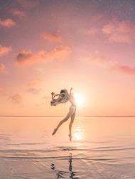 woman jumping on body of water