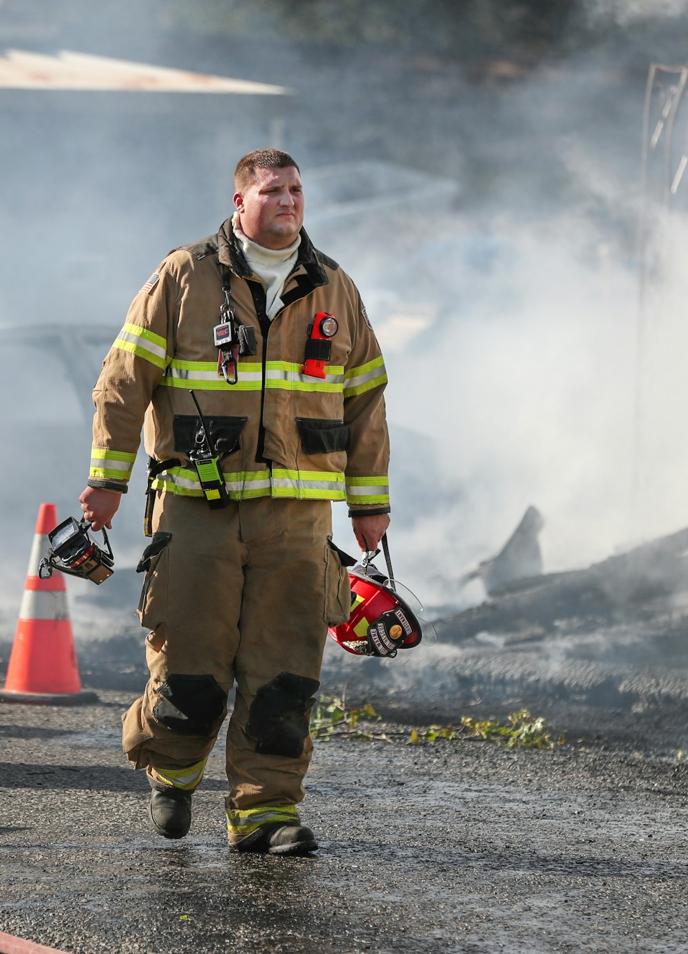 fireman holding helmet standing on road