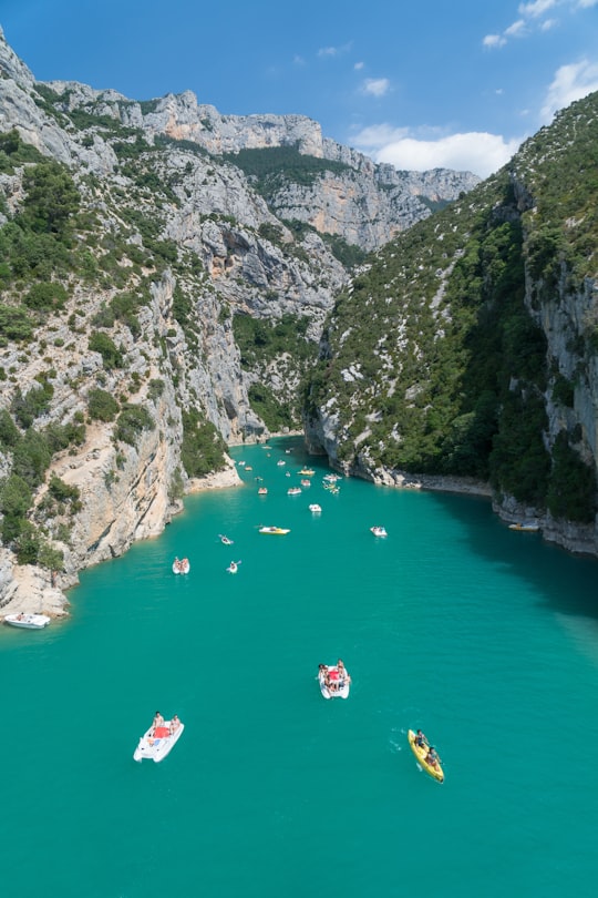 different boats on lake near mountain view under blue and white skies in Verdon Natural Regional Park France