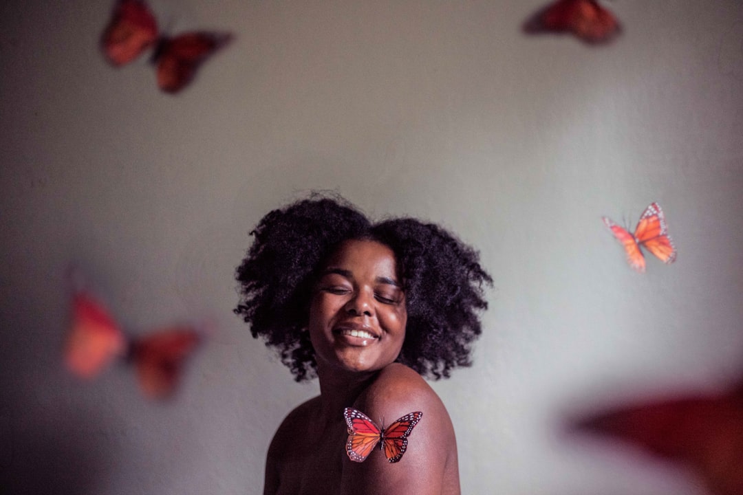 A black woman demonstrating self-acceptance - she has her natural hair out with a smile on her face.