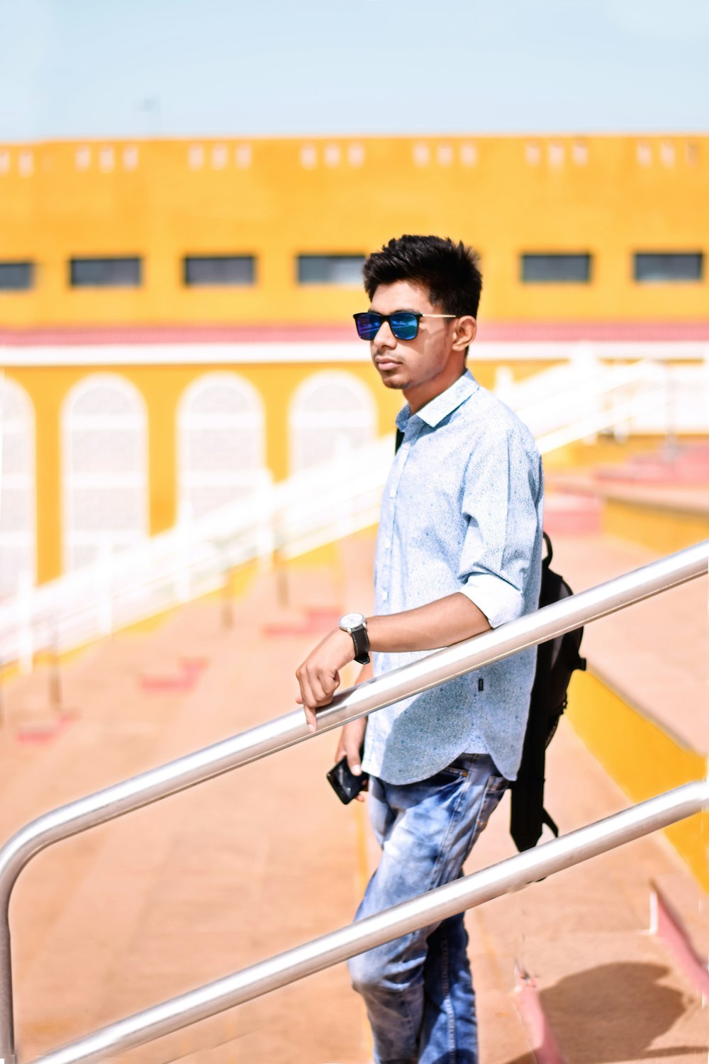 man wearing blue dress shirt holding on white railings during daytime