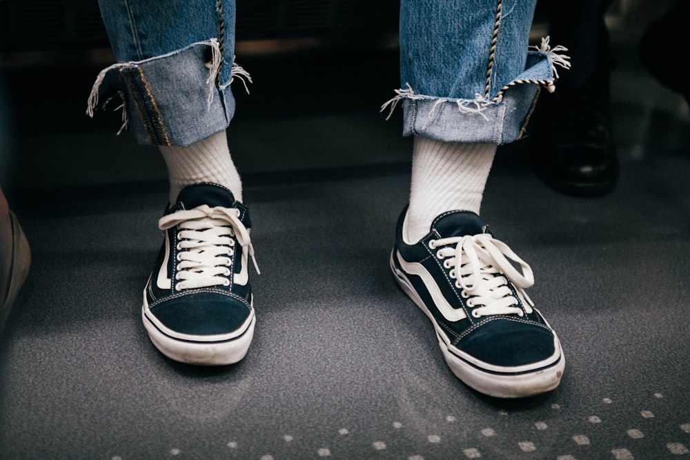 person in black-and-white Vans low-top sneakers