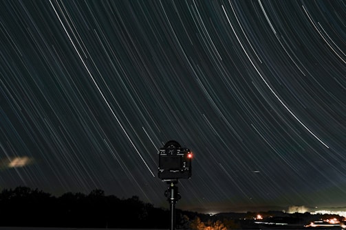A photographer setting up a tripod to capture star trails at night.