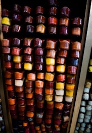 An array of colorful slippers is neatly arranged on shelves. The slippers come in various shades of red, yellow, orange, and brown, showcasing a vibrant and diverse collection.