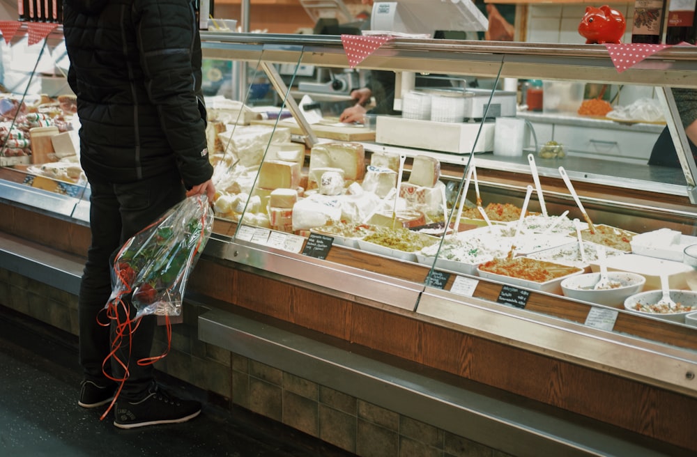 homme avec bouquet de roses debout devant l’étalage de nourriture