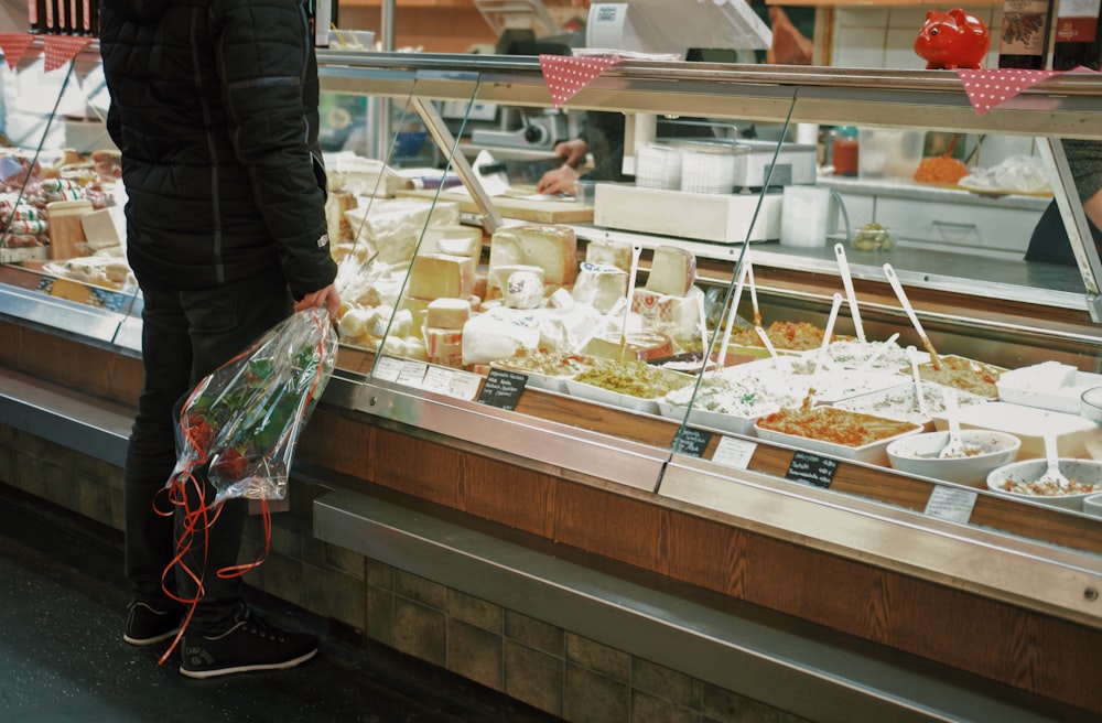 man with bouquet of roses standing in front of food display