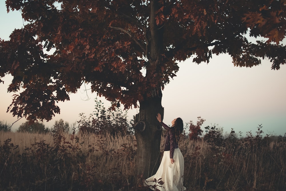 femme debout à côté d’un arbre brun